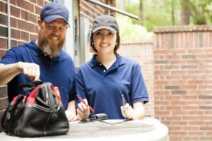 two-contractors-standing-near-ac-outdoor-unit-smiling