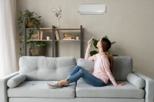 woman-using-remote-to-turn-on-ductless-air-handler-in-living-room