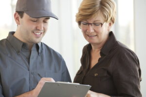 technician-showing-smiling-woman-something-on-a-clipboard